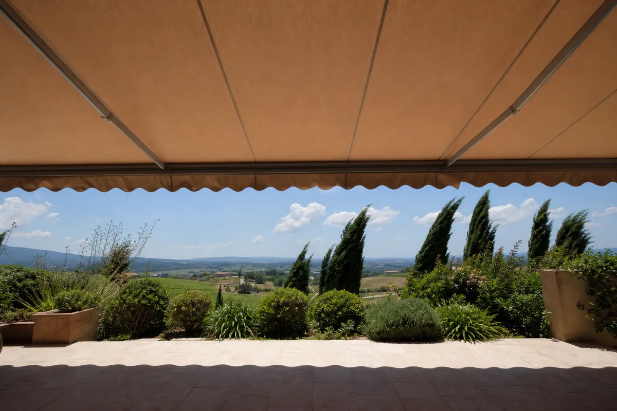 Store banne en aluminium déployé sur une terrasse méditerranéenne, toile tendue par la brise